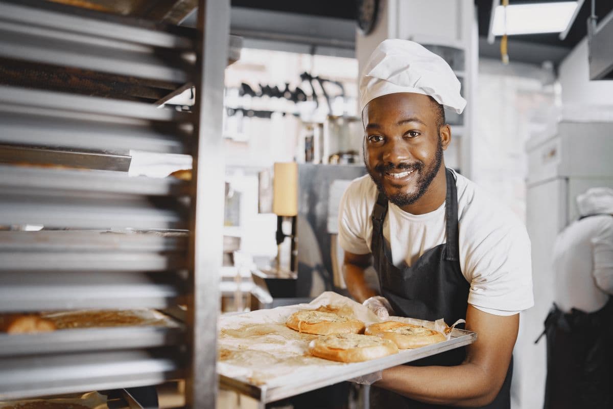 Boulanger souriant présentant ses pains dans son fournil